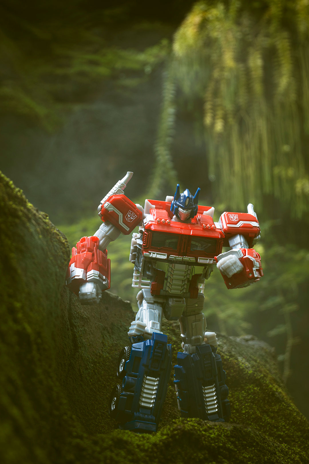 Toy photo of Optimus Prime walking in a forest scene. Hasbro Optimus Prime.